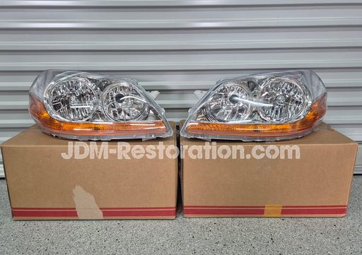 Two car headlights on cardboard boxes with 'JDM-Restoration.com' branding.