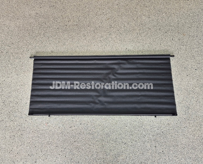 Black car cover with 'JDM-Restoration.com' text on a concrete surface
