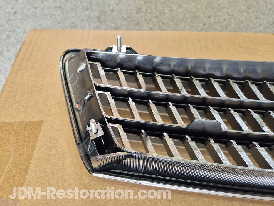 Car grille on a cardboard surface with 'JDM-Restoration.com' branding.