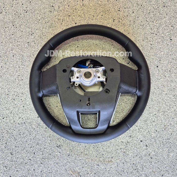 Steering wheel on a concrete floor with 'JDM Restoration' branding.