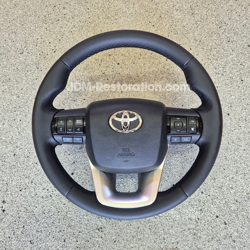 Black steering wheel with Toyota logo on a concrete surface