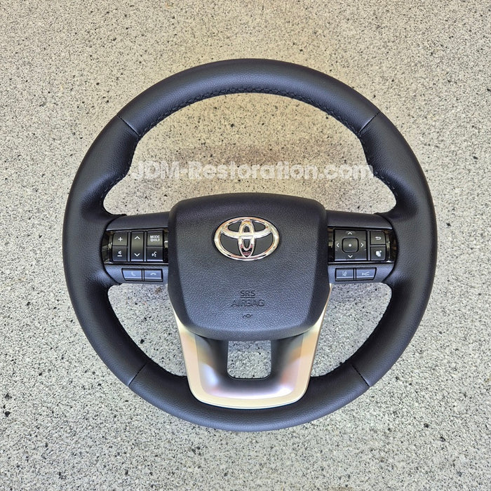 Black steering wheel with Toyota logo on a concrete surface