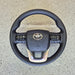 Black steering wheel with Toyota logo on a concrete surface