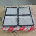 Four replacement air filters with white pleated paper and black frames, wrapped in clear plastic and resting on a cardboard box with a red and white Toyota pattern.