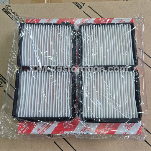 Four rectangular automotive air filters with white pleated media and black frames, sealed in clear plastic packaging with red-and-white branded paper bands. The filters are photographed on top of a brown cardboard box.