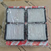 Four rectangular automotive air filters with white pleated media and black frames, sealed in clear plastic packaging with red-and-white branded paper bands. The filters are photographed on top of a brown cardboard box.