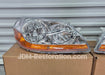 Car headlight on a cardboard box with 'JDM-Restoration.com' branding.